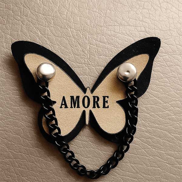 Aplique decorativo en forma de mariposa con cadena negra y fondo de cuero.