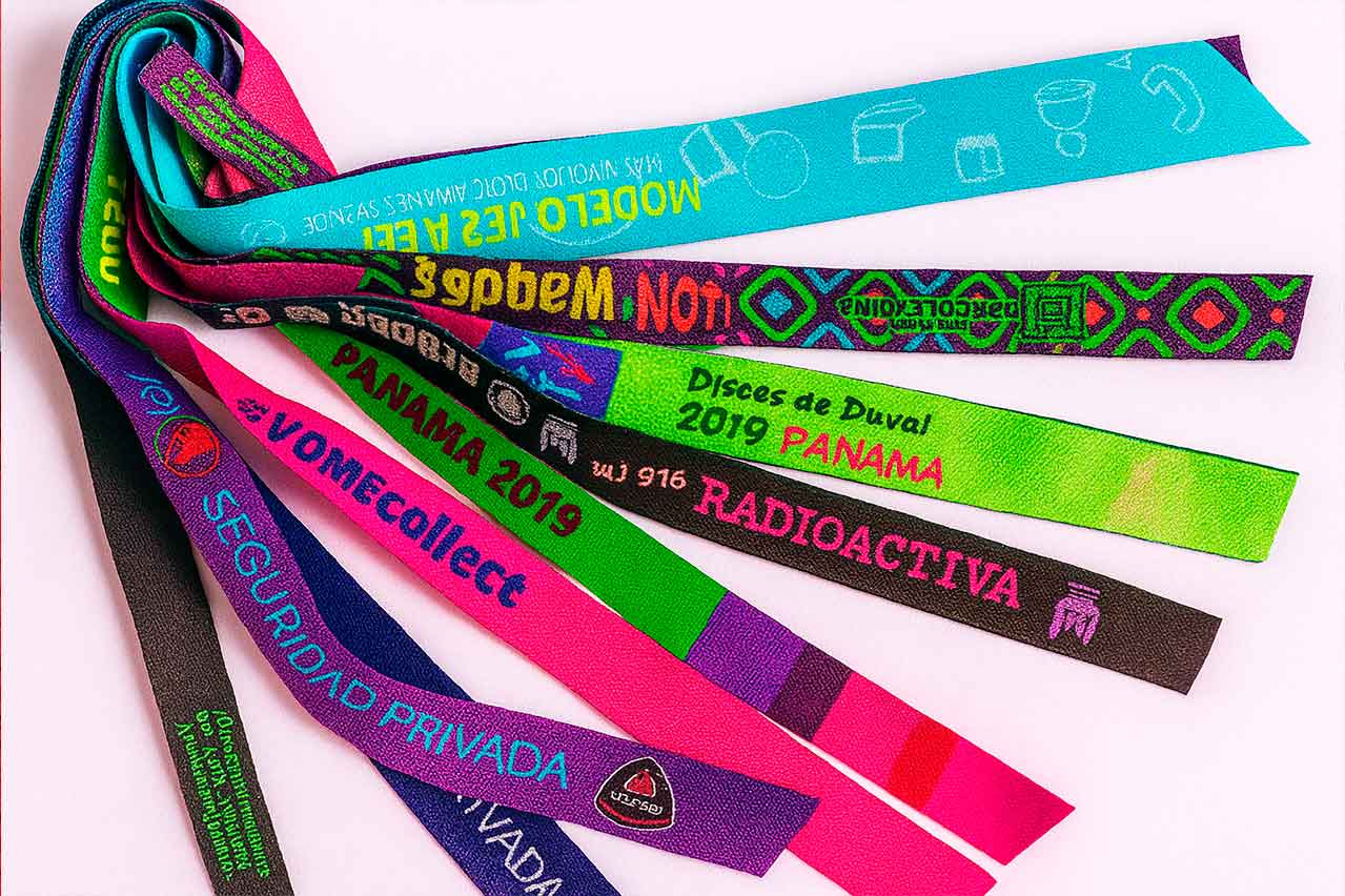 Manillas tejidas personalizadas con diseños y colores vibrantes para eventos, empresas y marcas, fabricadas en tela resistente sobre fondo blanco.