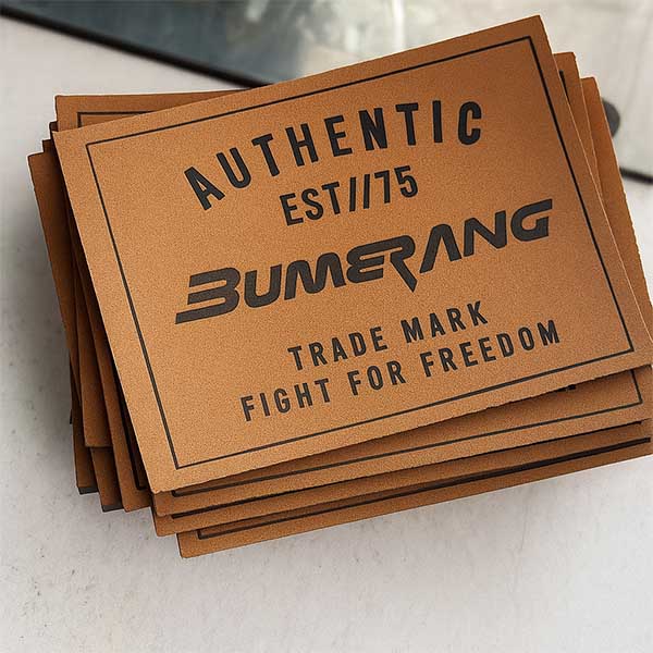 Fabricación de marquillas para jeans en Bogotá Aplique con grabado láser en marquilla rectangular de acabado sintético.